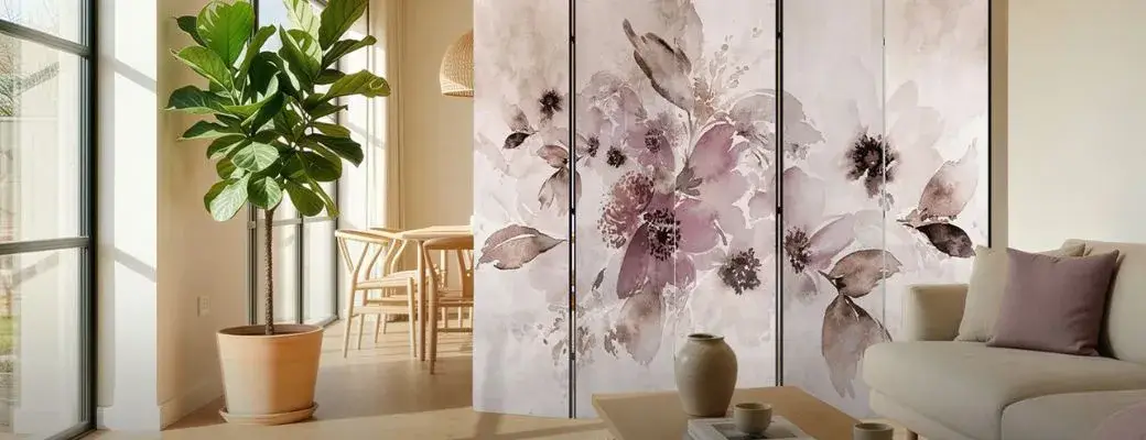 A room divider with a watercolour floral motif in shades of pink, purple and grey. The screen divides the open-plan living space, separating the lounge area with a sofa from the dining room, where a wooden table with chairs is visible.